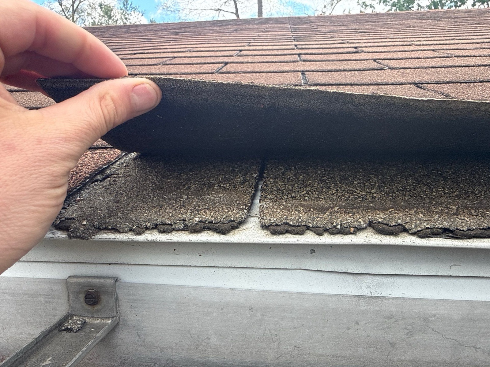 Brittle, unsealed shingles lifting at the eaves
